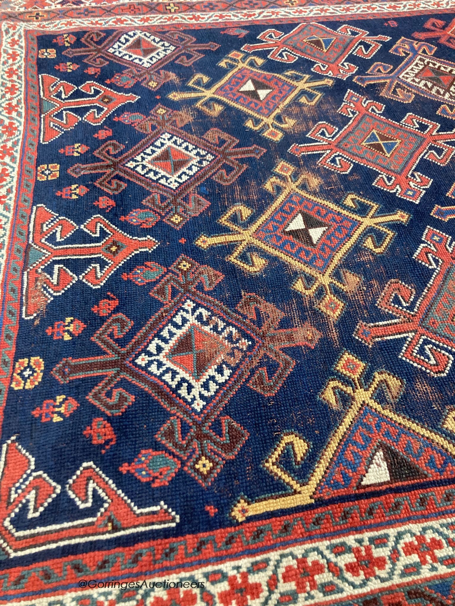 A Caucasian blue ground rug, woven with hooked lozenges, 288 x 152cm